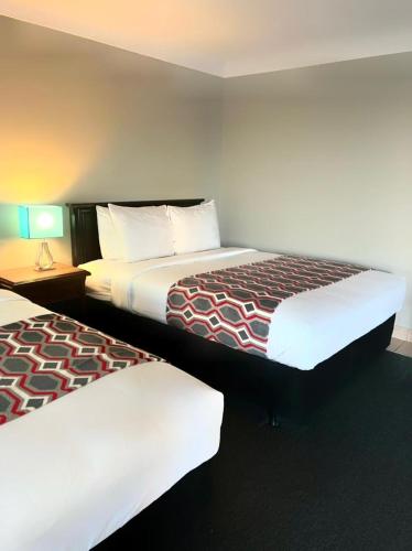伯灵顿City View Inn的酒店客房设有两张床和一张带台灯的桌子。