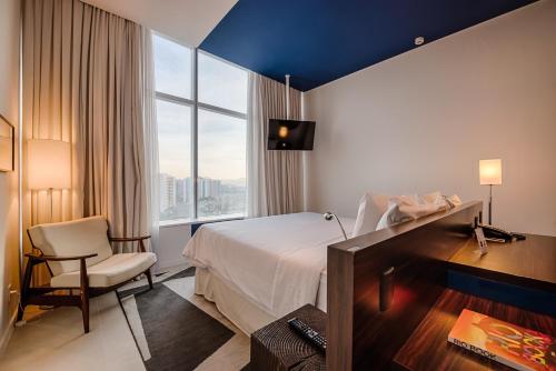 里约热内卢Lagune Barra Hotel的配有一张床、一张书桌和一扇窗户的酒店客房