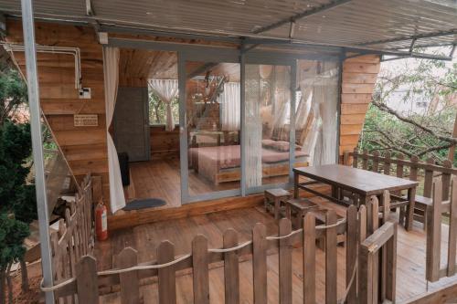 大叻Mơ Garden Retreat DaLat的小木屋设有桌子和甲板上的一张床
