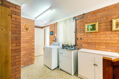 尼尔森湾3 Tomaree Street cute 4 bedroom house with aircon in the heart of town的厨房设有砖墙和水槽