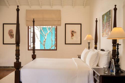尼甘布Uga Riva - Negombo的一间卧室配有一张带白色床单的床和一扇窗户。