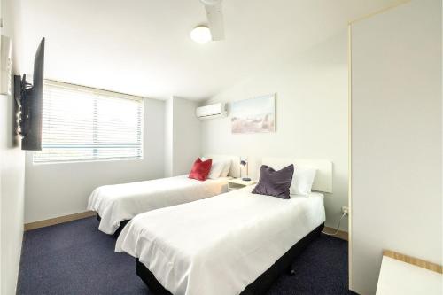 尼尔森湾Nelson Bay Breeze Apartment, 29,1 Trafalgar Street - Air conditioned unit with Linen supplied, complex pool and spa的白色墙壁客房的两张床