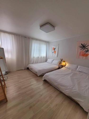 仁川市Reve Guwol的配有白色墙壁和木地板的客房内的两张床