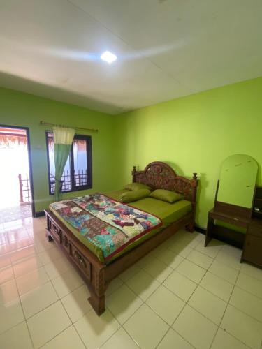卡里蒙贾瓦Ocean house karimunjawa的一间设有床铺的卧室,位于一个拥有绿色墙壁的房间