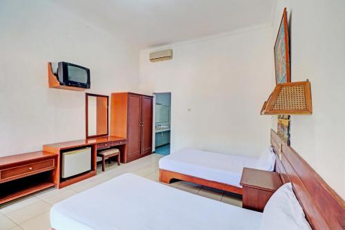 BanyubiruCapital O 93236 Hotel Hapel Negara的一间卧室配有一张床、一张书桌和一台电视。