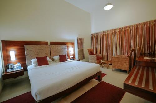 古鲁瓦尤尔Devaragam的酒店客房带一张大床和一把椅子