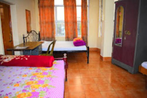 古瓦哈提Guwahati Lodge Guwahati的客房设有床、桌子和窗户。