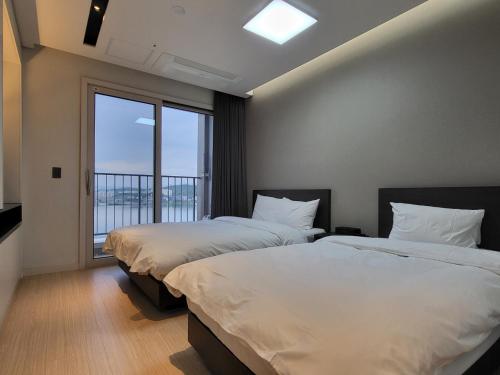 束草市World State Hotel Sokcho的带大窗户的客房内的两张床