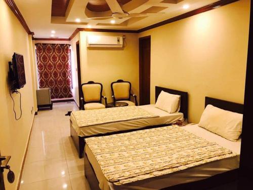 伊斯兰堡PAK HOTEL Islamabad的一间设有两张床和两把椅子的房间