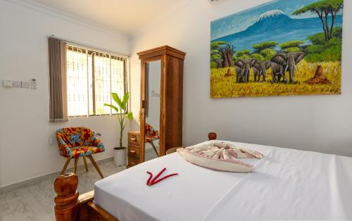 Kiembi SamakiShivo Guest House的卧室配有一张床,墙上挂有绘画作品