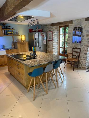 多尔多尼河畔博利厄Dordogne Farmhouse的厨房设有大岛,配有蓝色酒吧凳子
