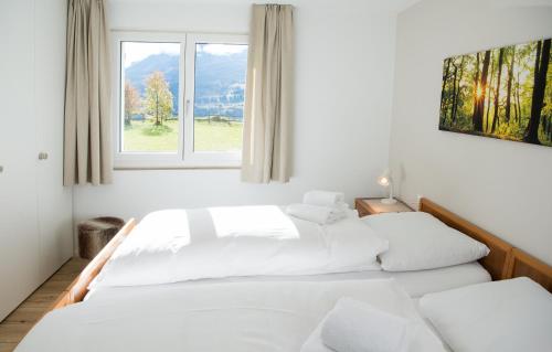 LenzFerienhaus mit Garten Tgease Schilendra-Lantsch-Lenz-Lenzerheide的白色客房的两张床,设有窗户