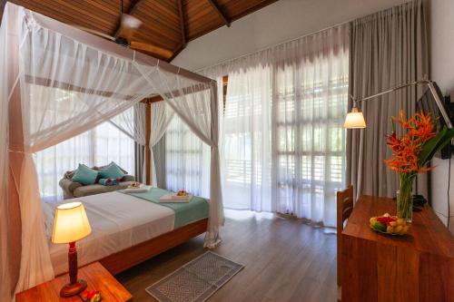 昂斯拉齐奥Anse Lazio Lodge的一间带天蓬床的卧室,位于带窗户的房间内