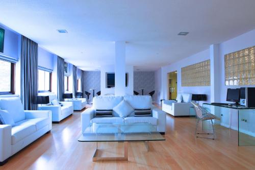 马德里马德里埃斯库埃拉酒店的大型客厅配有白色家具和窗户。