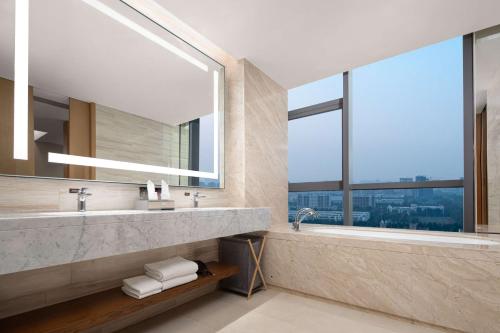 淄博淄博鼎成希尔顿花园酒店的一间带两个盥洗盆的浴室和一个大窗户