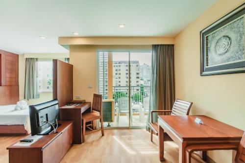 芭东海滩Bauman Residence Patong, Phuket的配有一张床和一张书桌的酒店客房