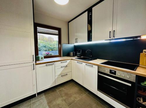 特劳特斯其岑Ferienhaus Ella的厨房配有白色橱柜和黑色用具