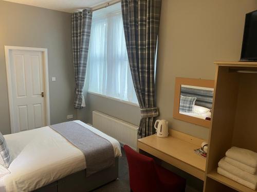 瑟索霍尔本酒店的一间卧室配有一张床、一张书桌和一个窗户。