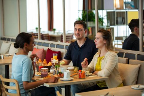吕姆朗IntercityHotel Zürich Airport的坐在餐厅桌子上的男人和女人