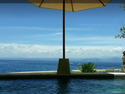 蓝梦岛Nusa Lembongan Villa Shambala的游泳池享有海景,配有遮阳伞