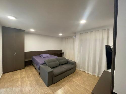 索罗卡巴Studio Super localizaçao的一间卧室配有一张床、一张沙发和一台电视