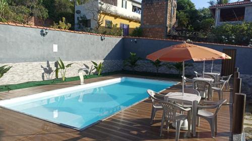 马塔迪圣若昂Residencial Jardim Imbassai 4 apt mobiliado com piscina的一个带桌椅和遮阳伞的游泳池