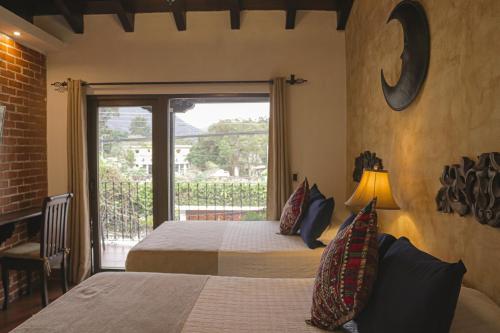 危地马拉安地瓜月光女神酒店的一间带两张床的卧室和通往阳台的门