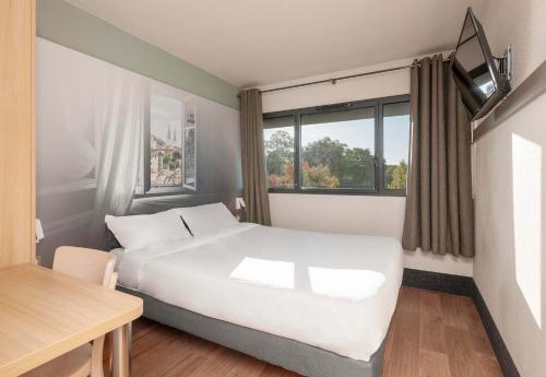 波城B&B HOTEL Pau Zénith的卧室配有一张白色的大床和一张桌子
