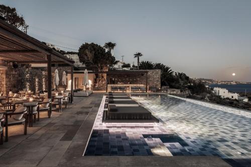 奥诺斯Enigma Mykonos Hideaway Suites的一座配有桌椅的酒店游泳池