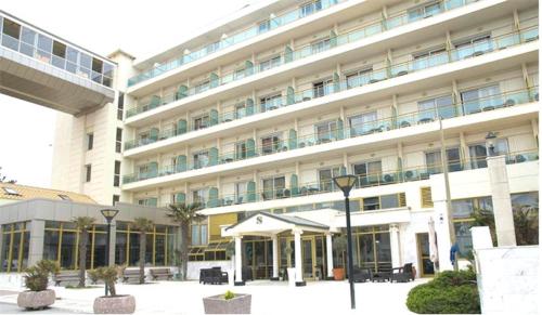 阿吉亚特拉萨三泰海滩酒店的一座白色的大建筑,前面有一个庭院
