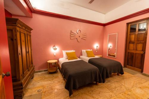 瓦哈卡市Viajero Oaxaca Hostel的一间设有两张床的客房和墙上的时钟