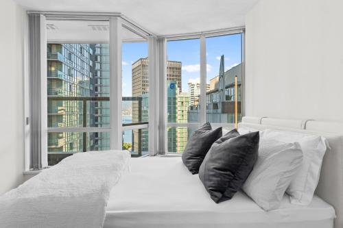 温哥华Downtown Luxury 1BR Coal Harbour的窗前带黑色枕头的白色床