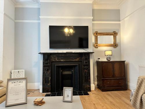 纽波特Victorian/modern house的客厅设有壁炉,配有一台平面电视