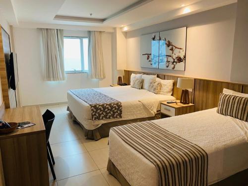 马卡埃Paradiso Macae Hotel的酒店客房设有两张床和电视。