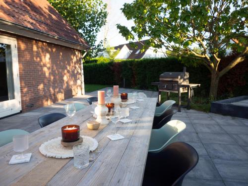 泽沃德Luxurious Family Villa with swimmingpool big garden and jacuzzi的一张长木桌子,上面摆放着椅子和蜡烛