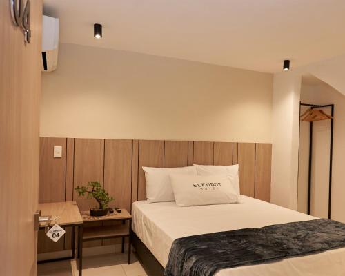 麦德林Elemont Hotel的一间卧室配有一张床和一张带枕头的桌子