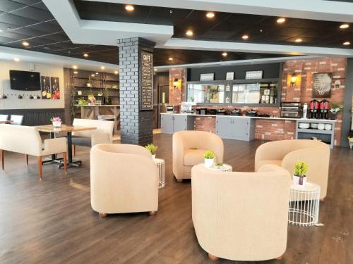 麦克默里堡优异套房酒店 的一间设有白色桌椅的餐厅和一间酒吧