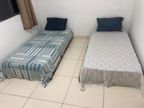 塞古罗港Tchê Hostel的两张睡床彼此相邻,位于一个房间里