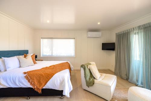 欧尼坦基Onetangi Beach Stays Studio 2 - Coast & Country的一间卧室配有一张大床和一把椅子