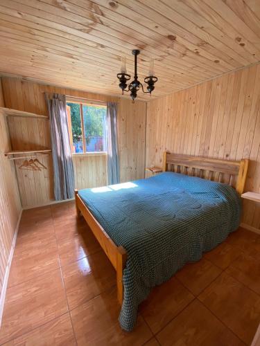 富特罗诺CABAÑAS RUCA MALAL的木制客房内的一间卧室,配有一张床