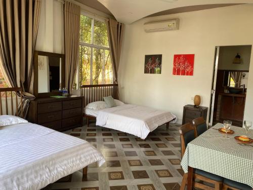 永隆Bình An Village的一间卧室配有两张床和一张桌子及椅子