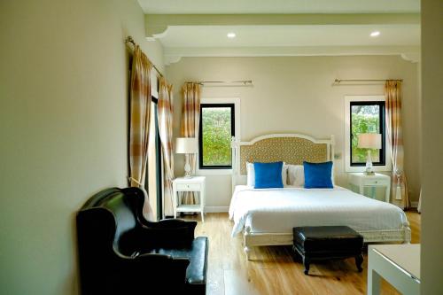 纳仲天赤湾尼芭堤雅酒店的一间卧室配有一张带蓝色枕头的床和一把椅子