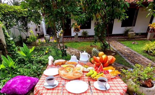 卡图纳耶克Dinu Lanka Resort的一张野餐桌,上面有盘子食物放在毯子上