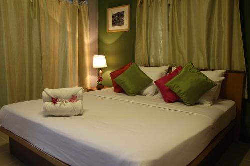 莱卡邦Plai And Herbs Suvarnabhumi Airport的卧室配有一张带彩色枕头的大型白色床。