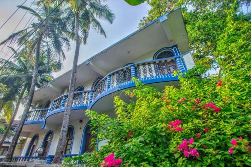 巴加Baga Beach Crystal的一座蓝白色的建筑,种植了棕榈树和粉红色的花卉