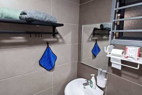 新山Homestay ARC_Cozyhome @ Austin Hills的浴室设有水槽和带蓝色毛巾的卫生间。