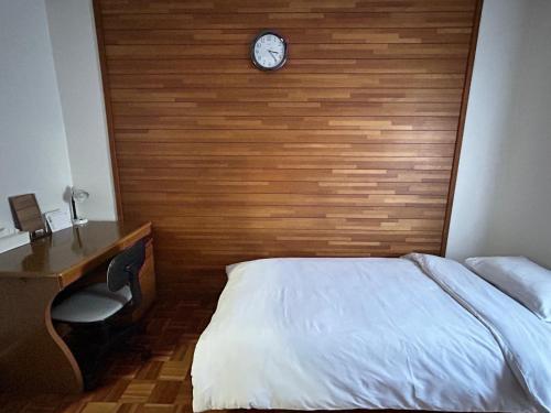 泉佐野KIX House Waraku III 和楽三号館的一间卧室,配有一张床,墙上挂着一个钟
