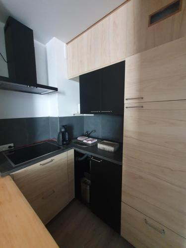 那慕尔Le Cosy - Queen-size, full équipé, wifi, parking的一间配备了黑色家电和木制橱柜的小厨房