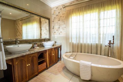克拉伦斯Andes Clarens Guesthouse的浴室设有2个水槽、浴缸和镜子