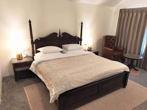 达兰萨拉Dev Bhoomi Farms & Cottages的一间卧室配有一张大床和一把椅子